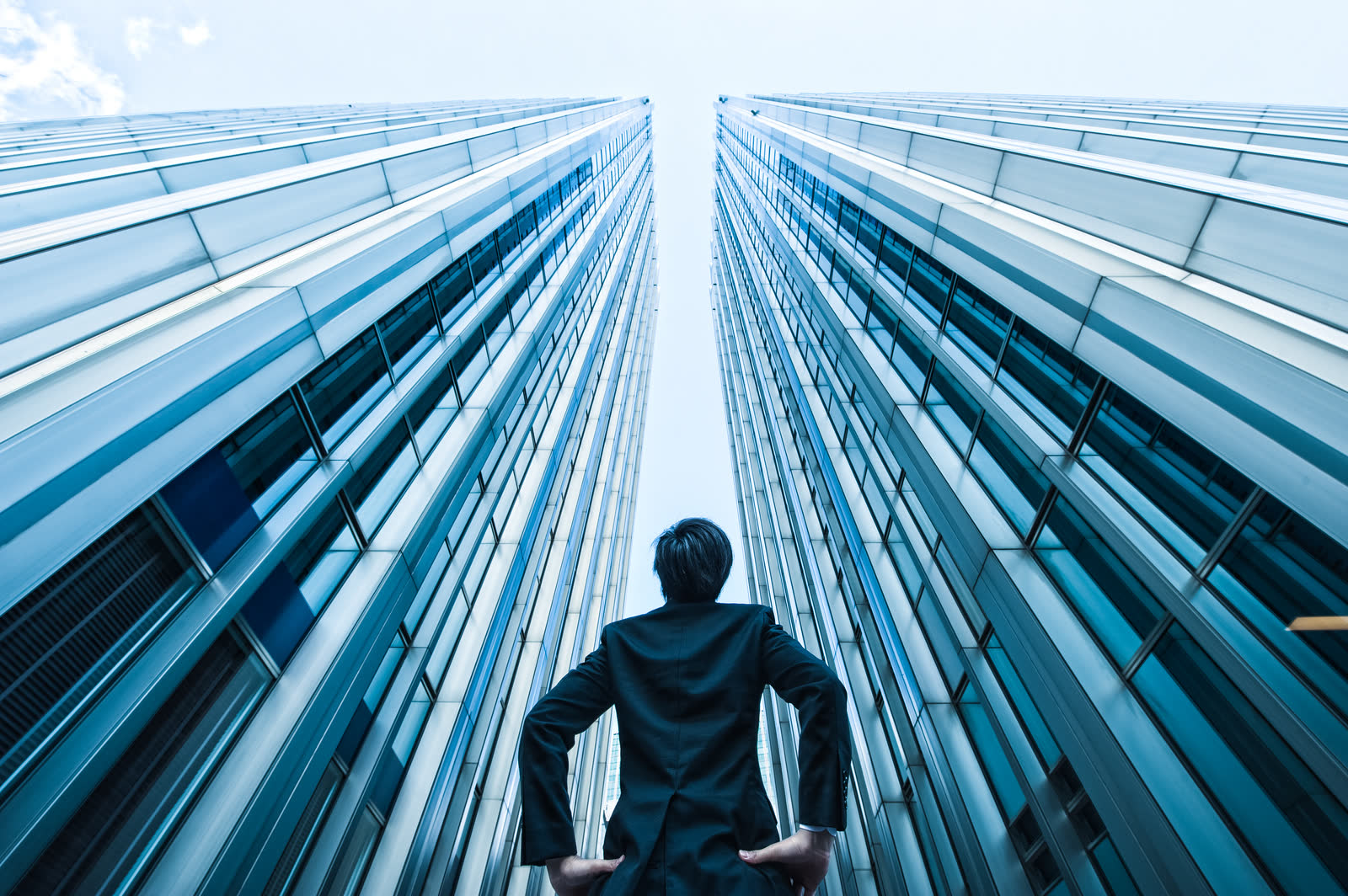 A businessperson looking up at high-rise buildings